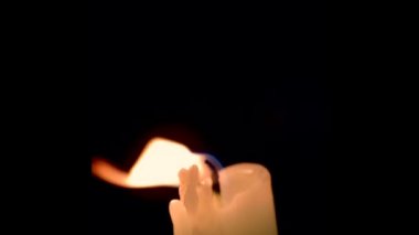 Siyah arka planda izole edilmiş yanan güzel bir mumun yakınında. Ateş alevlenir ve muhteşem bir şekilde söner..