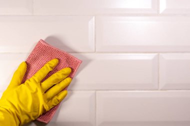 Seramik fayans yüzeyini pembe bir bezle silen sarı lastik bir eldiven verin. Mutfağın dezenfeksiyonu,