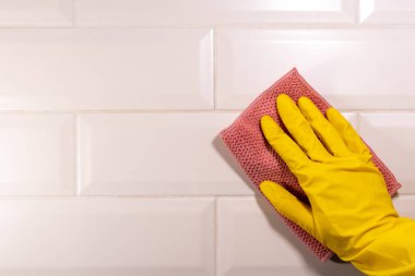 Seramik fayans yüzeyini pembe bir bezle silen sarı lastik bir eldiven verin. Mutfağın dezenfeksiyonu