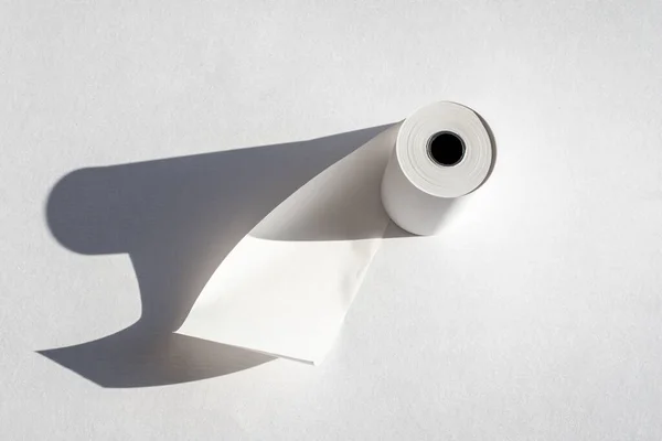 Рулон кассетной бумажной ленты с тенью на белой бумаге, копировальное место. Рулон кассовой кассы, бумажный рулон — стоковое фото