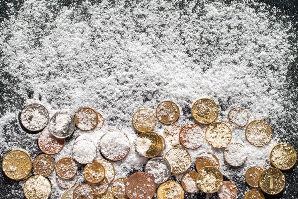 Coins covered with white sea salt such as snow on a black background. The concept of wealth and success — Stock Photo, Image