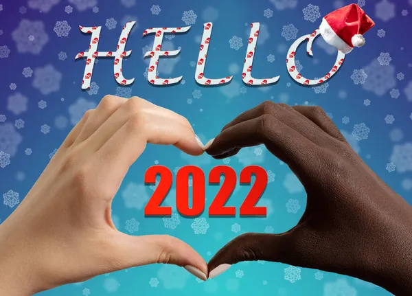 Mão preta e branca na forma de um coração e a inscrição HELLO 2022 e chapéu de Papai Noel em um azul — Fotografia de Stock