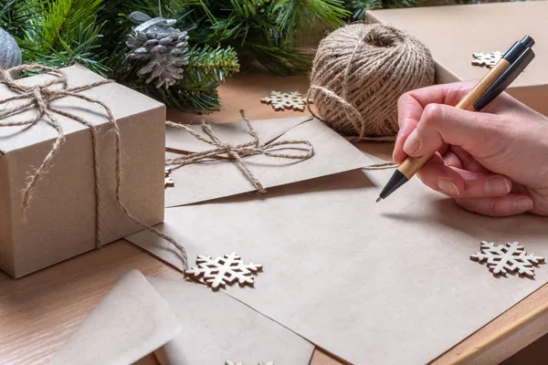 Una escritura a mano con un bolígrafo sobre papel reciclado vacío sobre una mesa con decoraciones navideñas. Planes de metas. Residuos cero — Foto de Stock