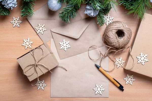 Regalos en cajas hechas a mano, papel reciclado, sobre, cordel, ramas de abeto artificial y copos de nieve de madera — Foto de Stock