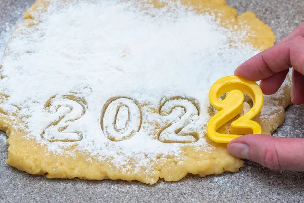 Escultura à mão de massa crua polvilhada com farinha branca como neve a data 2022 para Ano Novo e biscoitos de Natal. — Fotografia de Stock