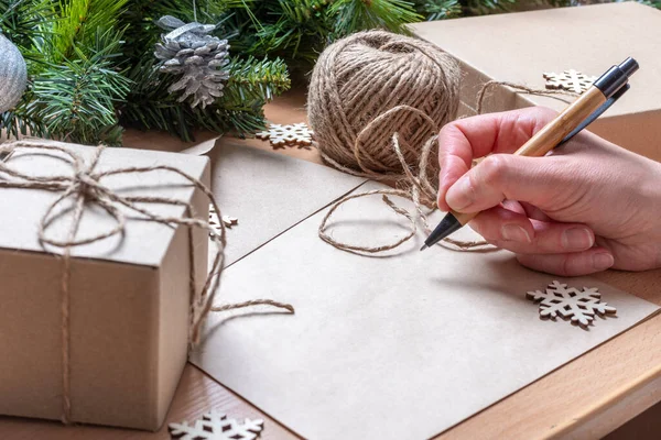 Escribir carta de Navidad - Escribir una carta con un bolígrafo en papel reciclado en blanco sobre una mesa con abeto con conos de pino —  Fotos de Stock
