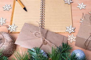 Boş defter, günlük, kalem, el yapımı kutular, köknar dalları ve tahta kar taneleri, düz döşeme, üst manzara, kopyalama alanı. Hediye listesi konsepti. Yeni yıl planlama konsepti