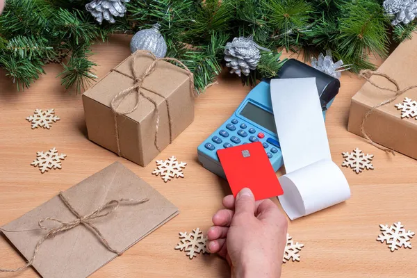 Noel hediyelerini tezgahta Noel süsüyle ödemek için kredi kartını EDC makinesinin üstünde ya da kasanın üstünde tutan kasiyer. Noel indirimi kavramı