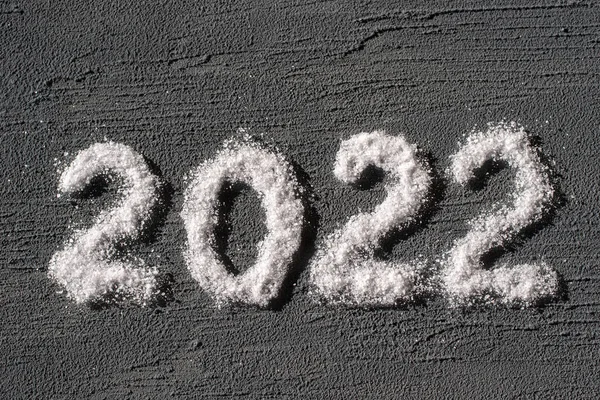 Boldog új évet 2022-ben. A dátum 2022 van írva só, mint a hó egy durva szürke vakolat háttér. Kreatív fedőlap tárgy képeslapokhoz — Stock Fotó