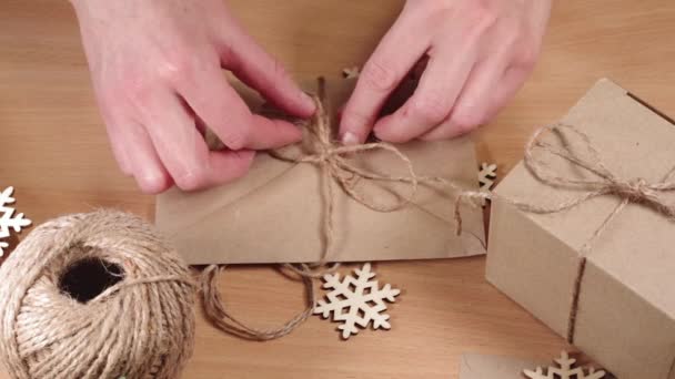 Handen zijn het inpakken van geschenken in een milieuvriendelijke stijl, Full HD. Zelfgemaakte cadeaus. Handen binden een strik om een envelop. — Stockvideo