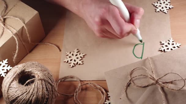 Escritura de cartas navideñas - Escritura a mano DEAR SANTA en marcador verde sobre papel reciclado en blanco sobre una mesa con abeto — Vídeo de stock