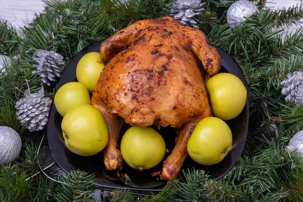 Рождественская еда. Жареная фаршированная курица, индейка с зелеными яблоками на праздничном столе с еловыми ветками и рождественскими украшениями — стоковое фото