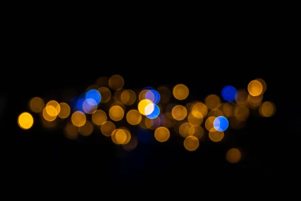 Beautiful background of defocused shiny blue and yellow round circles isolated on black background, festive bokeh for new year, christma. Horizontal stripe of blue and yellow shiny bokeh — Stock Photo, Image