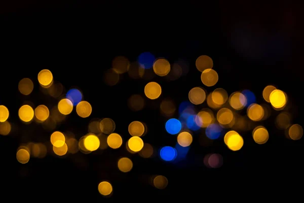 Красивий фон викривлених блискучих синьо-жовтих круглих кіл, ізольованих на чорному тлі, святковий боке на Новий рік, Різдво. Горизонтальна смуга блакитного і жовтого блискучого боке — стокове фото