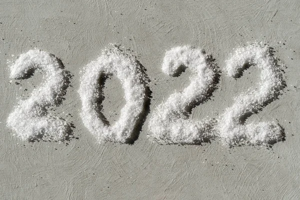 Feliz Ano Novo 2022. A data 2022 é escrita em sal como neve em um fundo de gesso cinza áspero. — Fotografia de Stock