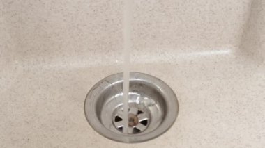 Su akıntısı lavaboya akıyor. Lavaboda akan su, yakın çekim, üst manzara