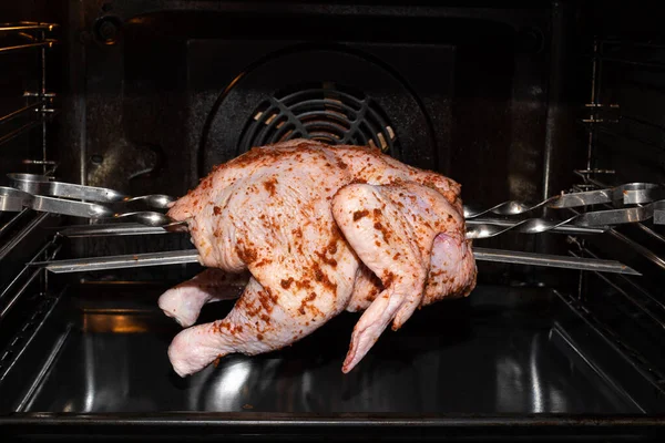 Pollo intero crudo viene fritto in forno, primo piano. Preparare un piatto di carne per un pranzo festivo. Cibo sano fatto in casa naturale — Foto Stock