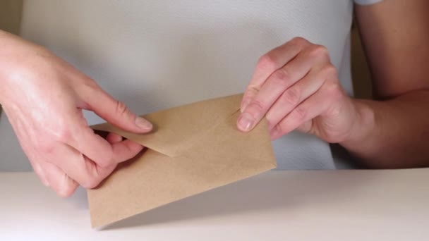 Las manos femeninas abren un sobre de papel marrón y sacan una carta, completa hd primer plano. Mujer feliz recibiendo carta manuscrita — Vídeos de Stock