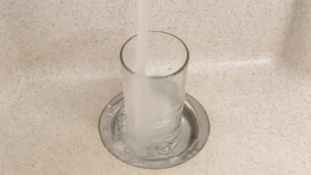 Fylla glaset med filtrerat renat kranvatten. Häll dricksvatten från kranen i ett genomskinligt glas. Kost mat. Begreppet hälsovård och användning av rent vatten. — Stockvideo
