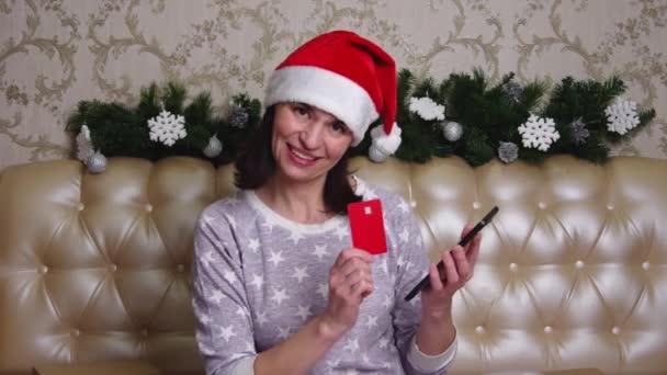 Een vrouw shopaholic maakt online aankopen bij een kerst internet verkoop, voert financiële gegevens van een bankkaart. Kerstmis online winkelen concept — Stockvideo