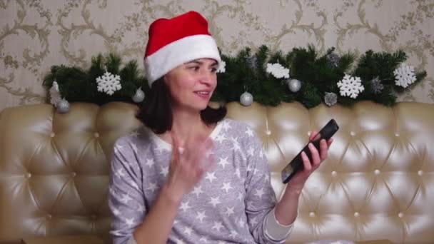 Pijamalı, orta yaşlı ve Noel Baba şapkalı bir kadın arkadaşlarıyla video görüşmesi yapıyor. — Stok video