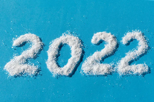 Feliz Ano Novo 2022. A data de 2022 está escrita em sal como neve sobre um fundo azul. Objeto de sobreposição criativa para cartões postais — Fotografia de Stock