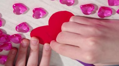 El yazısı yazıyorum. Seni seviyorum. Masada pembe kalplerle kırmızı kağıt kalp şeklinde. Sevgililer Günü için ev yapımı sevgililer günü kartı.