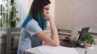 Mavi saçlı, dizüstü bilgisayarda yazan, kahve içen, esneyen ve uykuya dalan yorgun bir kız..