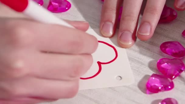 Hand writing the text YOU in red marker on the drawn heart shape on paper on the table. Homemade gift for valentines day — Wideo stockowe