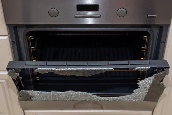 Opened broken oven door in the kitchen, top view, close-up. Broken glass from overheating. Broken glass from impact. Warranty repair. Repair of electric stoves and ovens