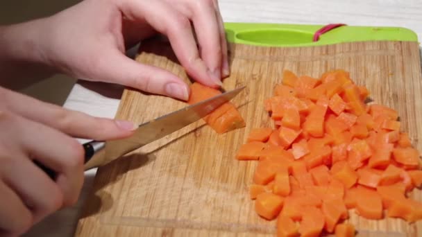 Close-up de um chefs mãos cortando cenouras cozidas com uma faca em uma tábua de corte de madeira, vista superior, hd completo. Processo de cozedura, conceito de alimentação saudável. — Vídeo de Stock