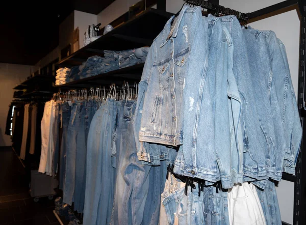 Mnoho džínových vest visí na ramínku v obchodě. Různé modré džínové bundy na ramínku v obchodě s oblečením. Obchod s džínama. obchodní koncept — Stock fotografie