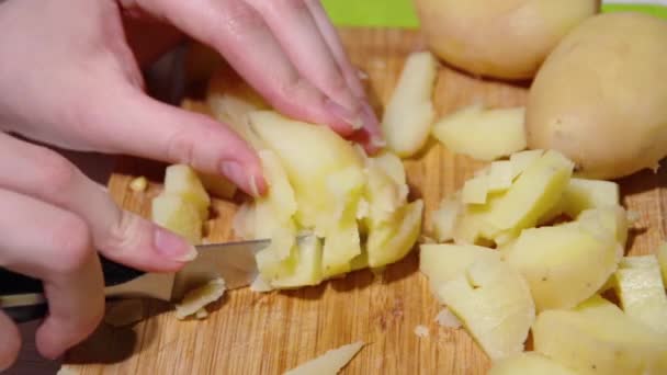 Close-up de um chefs mãos cortando batatas cozidas com uma faca em uma tábua de corte de madeira, hd completo. — Vídeo de Stock