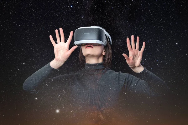 Una hermosa mujer con un casco de realidad virtual futurista o gafas 3D toca el espacio. Chica sorprendida en gafas vr en la magia del espacio — Foto de Stock