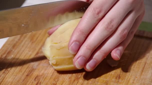 Close-up de um chefe mãos cortando batatas cozidas com uma faca em uma tábua de corte de madeira — Vídeo de Stock