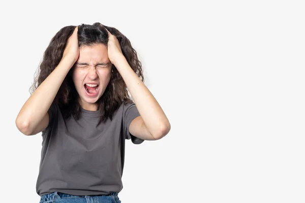 Enojada gritando adolescente sufriendo de soledad, sosteniendo su cabeza con sus manos sobre un fondo claro —  Fotos de Stock