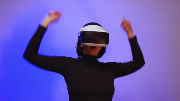 Happy girl di virtual reality helm mengangkat tangannya, menari, ungu neon cahaya, hd penuh. Konsep alam semesta maya — Stok Video