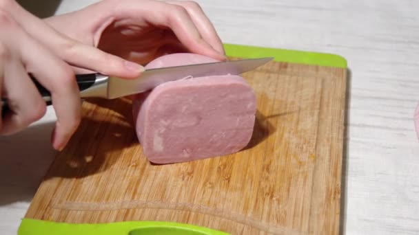 Close-up of a chefs hands cutting ham with a knife on a wooden cutting board, full hd. The process of preparing dinner — Stock Video