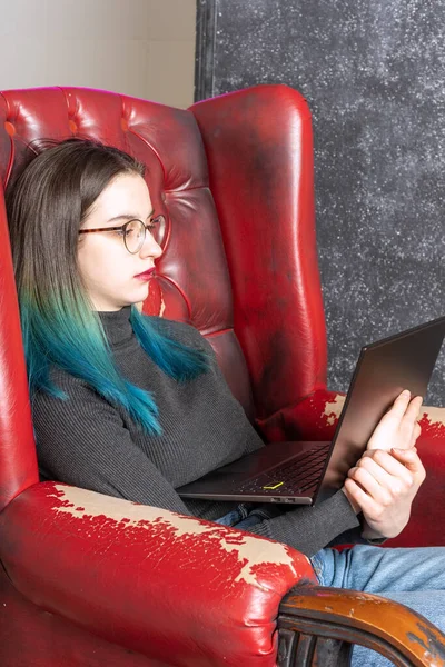 Adolescente cansada mirando un portátil mientras está sentada en una silla. Burnout mientras estudias. El concepto de salud mental — Foto de Stock