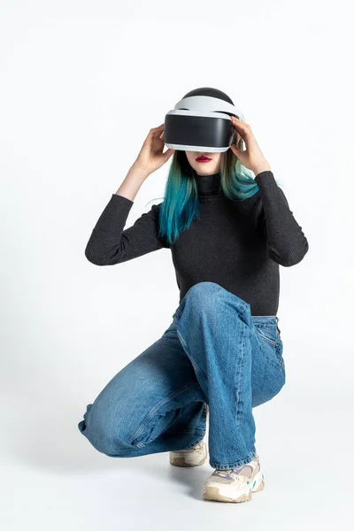 Una adolescente se pone un casco vr para entrar en el universo virtual aislado sobre un fondo blanco. Estilo de vida en el espacio virtual — Foto de Stock