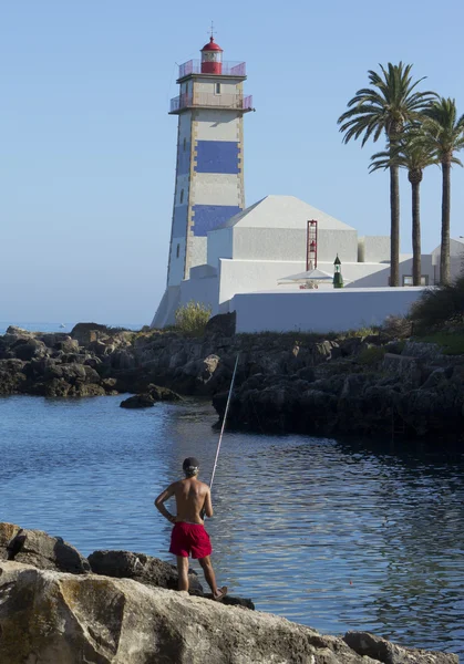 Der Fischer am Leuchtturm im Hintergrund des Ozeans bei Sonnenuntergang — Stockfoto