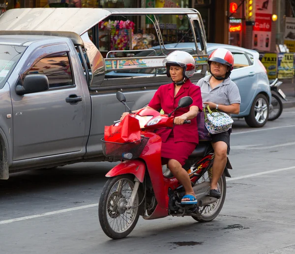 Zwei Frauen fahren nachmittags mit dem kleinen Motorrad die Straße hinunter — Stockfoto