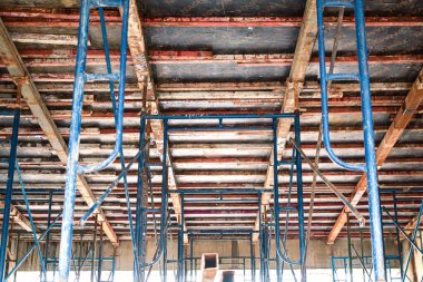 Yüksek binaların beton işçiliğini desteklemek için çelik iskeleler kuruyor. Beton zemini desteklemek için zeminin altında bir manzara. İkinci kata beton dökme formu hazırlanıyor..