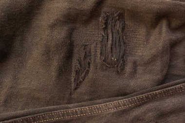 Siyah kotun tamiri. Siyah kotların yüzeyinde delikler, iplikler ve onarımlardan kalan dikişler var. Denim mavi kot, Makro çekimi kapat, soyut tekstil dokusu arkaplanı.
