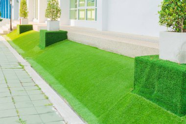 Arkaplan için yapay yeşil çim. Güzellik için beton zemine yapay çimen döşemeleri seriyorum..