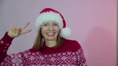 Noel Baba şapkalı çekici bir kadın Noel 'i kutluyor, dans ediyor, gülümsüyor ve eğleniyor. Yavaş çekim.