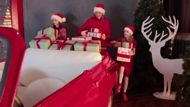Щаслива сім'я поклала різдвяні подарунки на червону машину — стокове відео
