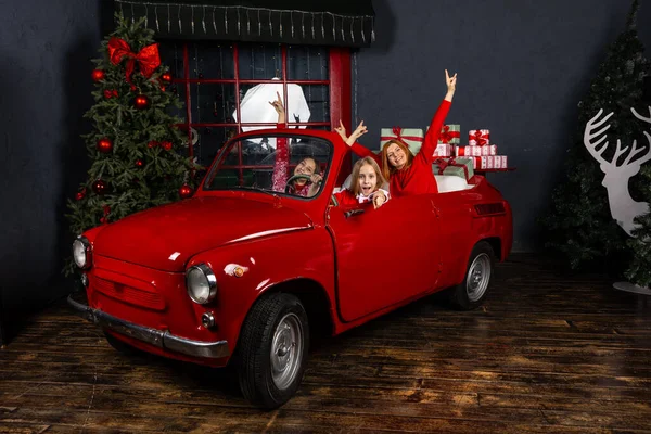 Joyeux Noël et la livraison du Nouvel An. Filles en rouge vintage voiture livre des cadeaux — Photo