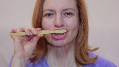  Close up middle age woman brushing teeth with toothpaste.