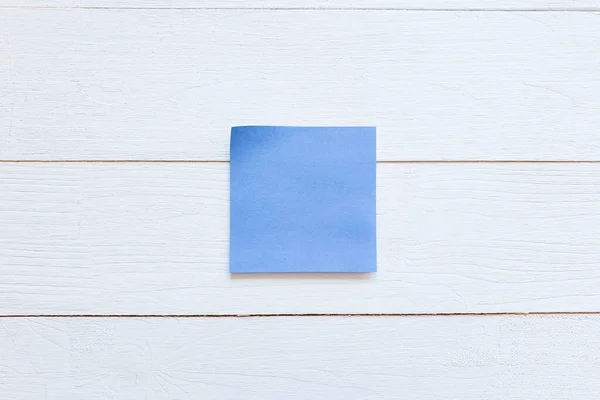 白色木板墙上有一张蓝色的纸贴纸 顶部视图 复制空间 — 图库照片